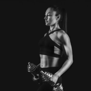 strong fit woman with dumbbells black background woman bodybuilder portrait low key copy space monochrome scaled e1645109495926